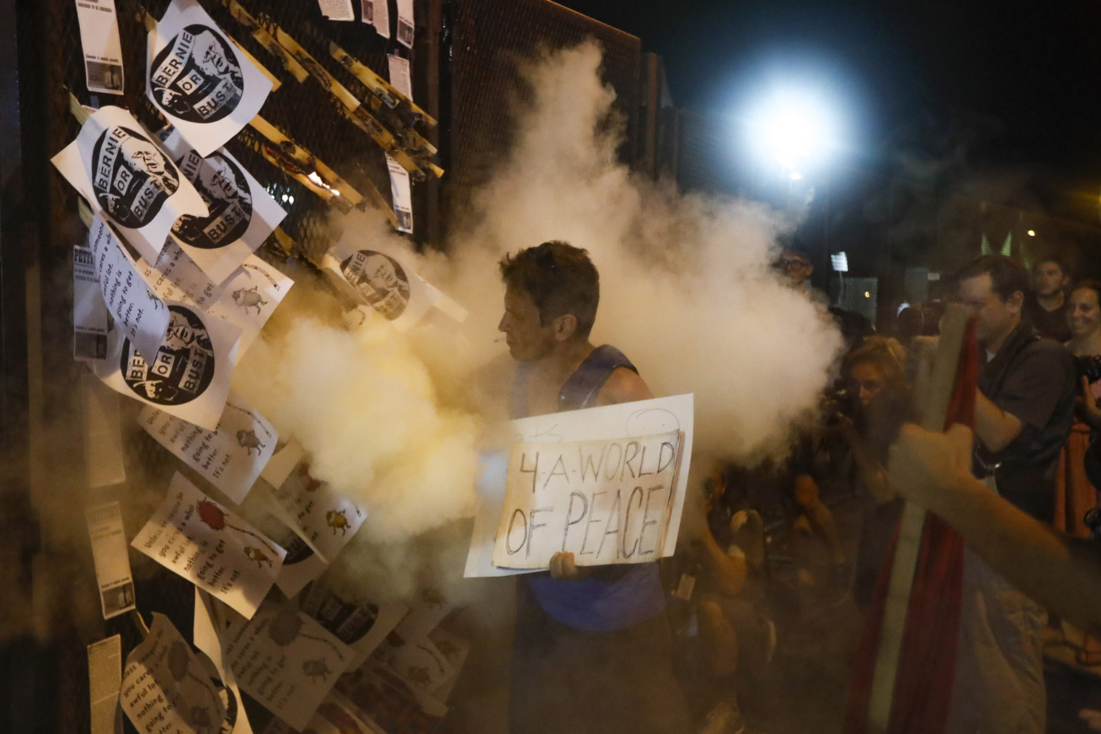 A demonstrator is enveloped in a cloud of fire extinguisher as fliers stuck into a police barricade bearing "Bernie or Bust" logos burn near AT&amp;T Station during a protest in Philadelphia, Tuesday, July 26, 2016, during the second day of the Democratic National Convention. (AP Photo/John Minchillo)