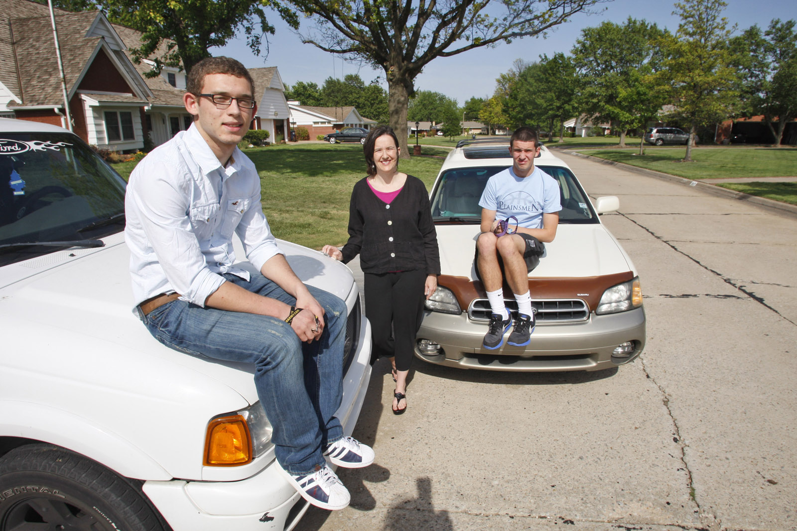 In this May 17, 2011 photo, David Helm, left, Molly Helm, center, and Harrison Maud pose with the boys' automobiles in Enid, Okla. As every driver quickly learns, operating costs are just the beginning. Add in ownership costs like insurance and registration fees and the costs quickly climb _ to an average $8,776 per year, or 58.5 cents per mile, for a car driven 15,000 miles annually.(AP Photo/Sue Ogrocki)