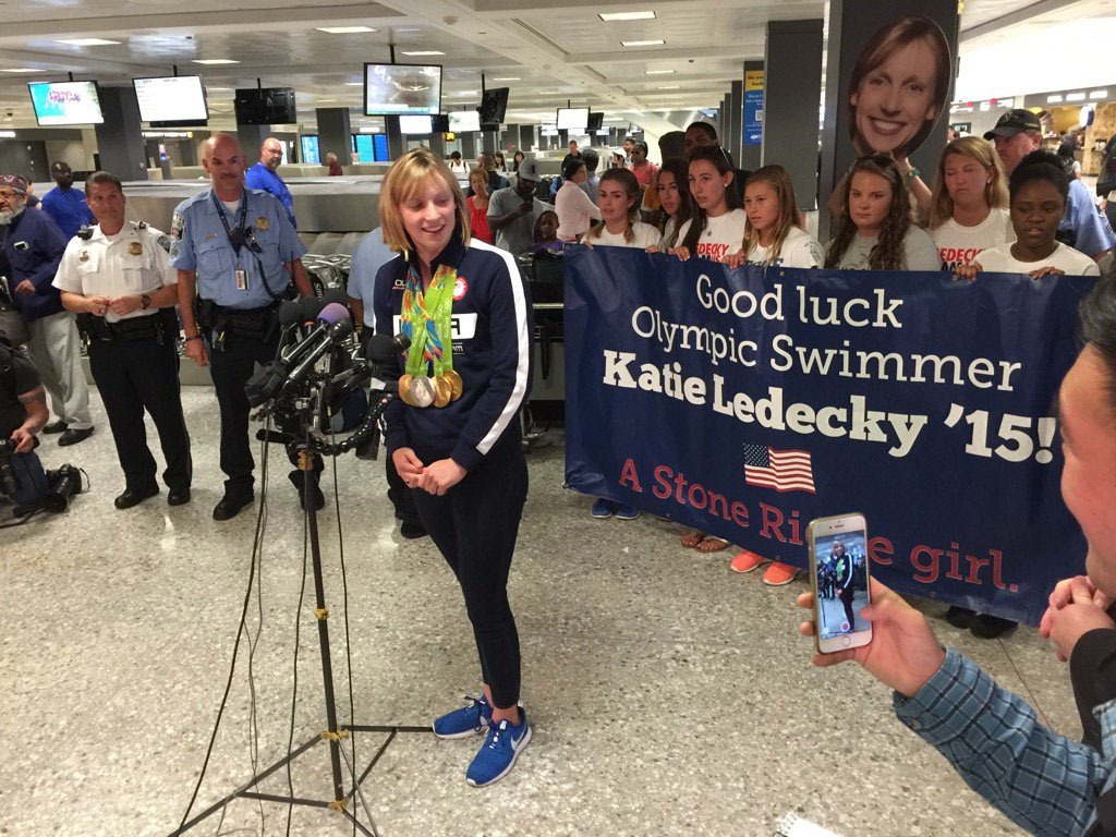 Flanked by fans and well-wishers at Dulles International Airport, Olympic swimmer Katie Ledecky answers questions from the media. (WTOP/Katie Ledecky)