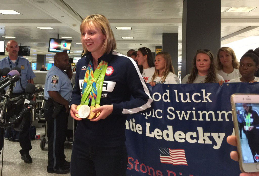 Five-time Olympic gold medalist Katie Ledecky displays her medals for the media at Dulles International Airport after returning from Rio. Ledecky says fellow U.S. swimmer Michael Phelps taught her how to display her medals. (WTOP/Kristi King)