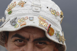 A man wearing a hat with pins poses for a picture outside the Olympic village ahead of the 2016 Summer Olympics in Rio de Janeiro, Brazil, Wednesday, Aug. 3, 2016. The Games opening ceremony is on Friday.(AP Photo/Natacha Pisarenko)