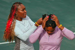 Venus Williams of the United States, left, helps her sister Serena Williams adjust her hair before a practice session on the central court ahead of the upcoming 2016 Summer Olympics in Rio de Janeiro, Brazil, Wednesday, Aug. 3, 2016. (AP Photo/Vadim Ghirda)