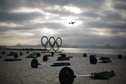 Umbrellas lay on the sand at the sailing venue as a plane takes off in the distance at the 2016 Summer Olympics in Rio de Janeiro, Brazil, Tuesday, Aug. 9, 2016. (AP Photo/David Goldman)