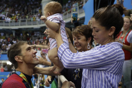 United States' Michael Phelps celebrates winning his gold medal in the men's 200-meter butterfly with his mother Debbie, fiance Nicole Johnson and baby Boomer during the swimming competitions at the 2016 Summer Olympics, Tuesday, Aug. 9, 2016, in Rio de Janeiro, Brazil. (AP Photo/Matt Slocum)