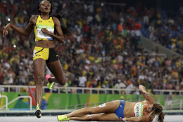 Second placed Netherlands' Dafne Schippers lies on the ground after falling over the finish line as Elaine Thompson from Jamaica, left, wins the gold in the women's 200-meter final during the athletics competitions of the 2016 Summer Olympics at the Olympic stadium in Rio de Janeiro, Brazil, Wednesday, Aug. 17, 2016. (AP Photo/David J. Phillip)