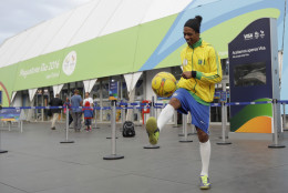 Robinson Oliveira, who works as a professional lookalike of the Brazilian soccer star Ronaldinho kicks a ball in front of a souvenir store for the 2016 Summer Olympics along Copacabana beach in Rio de Janeiro, Brazil, Wednesday, Aug. 3, 2016. The Olympics are scheduled to open Aug. 5. (AP Photo/Gregory Bull)