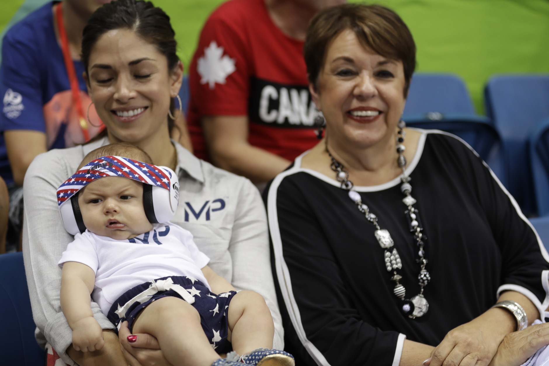 United States' Michael Phelps' son Boomer, with his fiancee Nicole Johnson and mother Debbie, wears ear protection during the swimming competitions at the 2016 Summer Olympics, Monday, Aug. 8, 2016, in Rio de Janeiro, Brazil. (AP Photo/Michael Sohn)