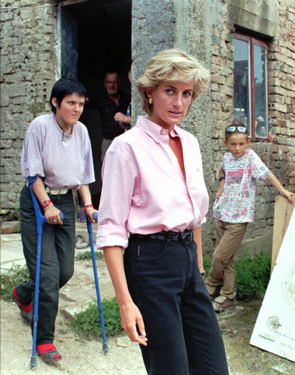 Britain's Diana Princess of Wales, center, folowed by Mirzeta Gabelic, left, a 15 year-old land mine victim, leaves her home in Sarajevo, Sunday August 10, 1997. Diana is on three-day visit to Bosnia-Herzegovina, to focus world attention on the continuing plaque of land mines and to call for a complete ban on the production, sale and use of land mines.(AP PHOTO/Hidajet Delic)