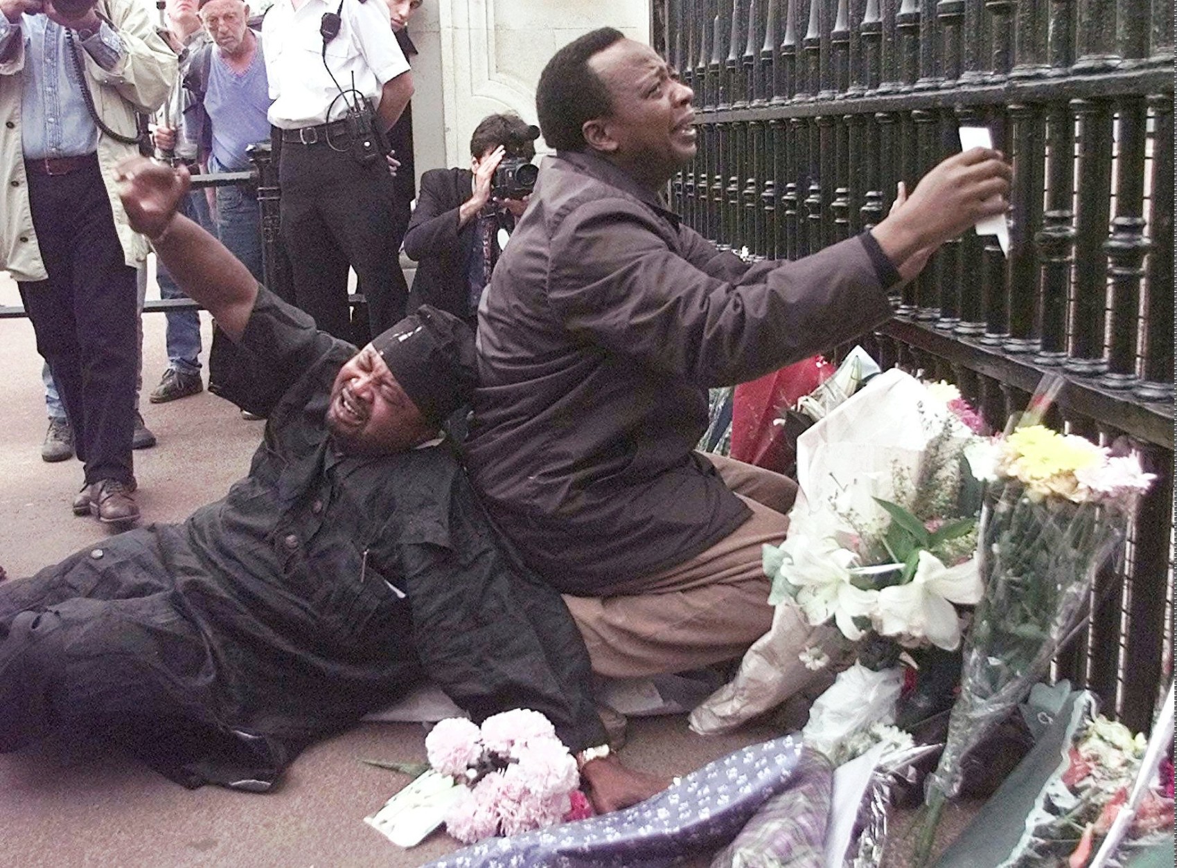 Two men grieve at the gate of Buckingham Palace in London  Sunday, August 31, 1997 after laying flowers for Diana, Princess of Wales, who was killed in a car crash with her comapnion Dodi Fayed in Paris early Sunday morning.  (AP Photo/Lynne Sladky)