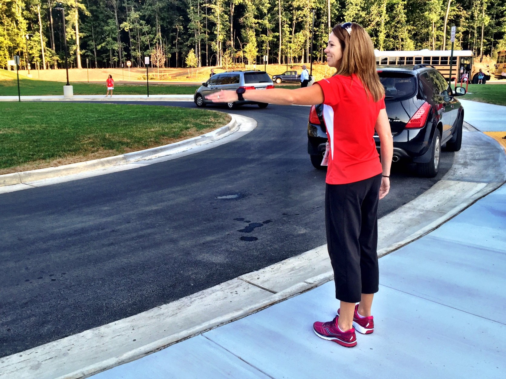 Physical education teacher Beth Ciccone directs in the dropoff lane on the first day of school at Madison's Trust Elementary, in Loudoun County. (WTOP/Neal Augenstein)