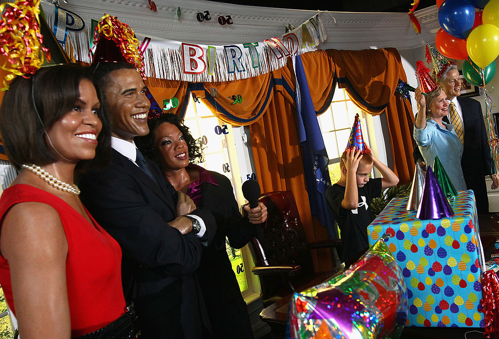 WASHINGTON, DC - AUGUST 04:  Andrew Korakis (C), from New York, puts on a party hat while visiting a replica of the Oval Office with wax figures of (L-R) U.S. first lady Michelle Obama, President Barack Obama and Oprah Winfrey at Madame Tussauds Wax Museum on Obama's 50th birthday August 4, 2011 in Washington, DC. On Obama's 50th birthday, the replica Oval Office at Madame Tussauds was decorated with party balloons, streamers and presents, while the figures the Obamas, Bill and Hillary Clinton and Oprah Winfrey were outfitted with party hats and noisemakers. .  (Photo by Win McNamee/Getty Images)