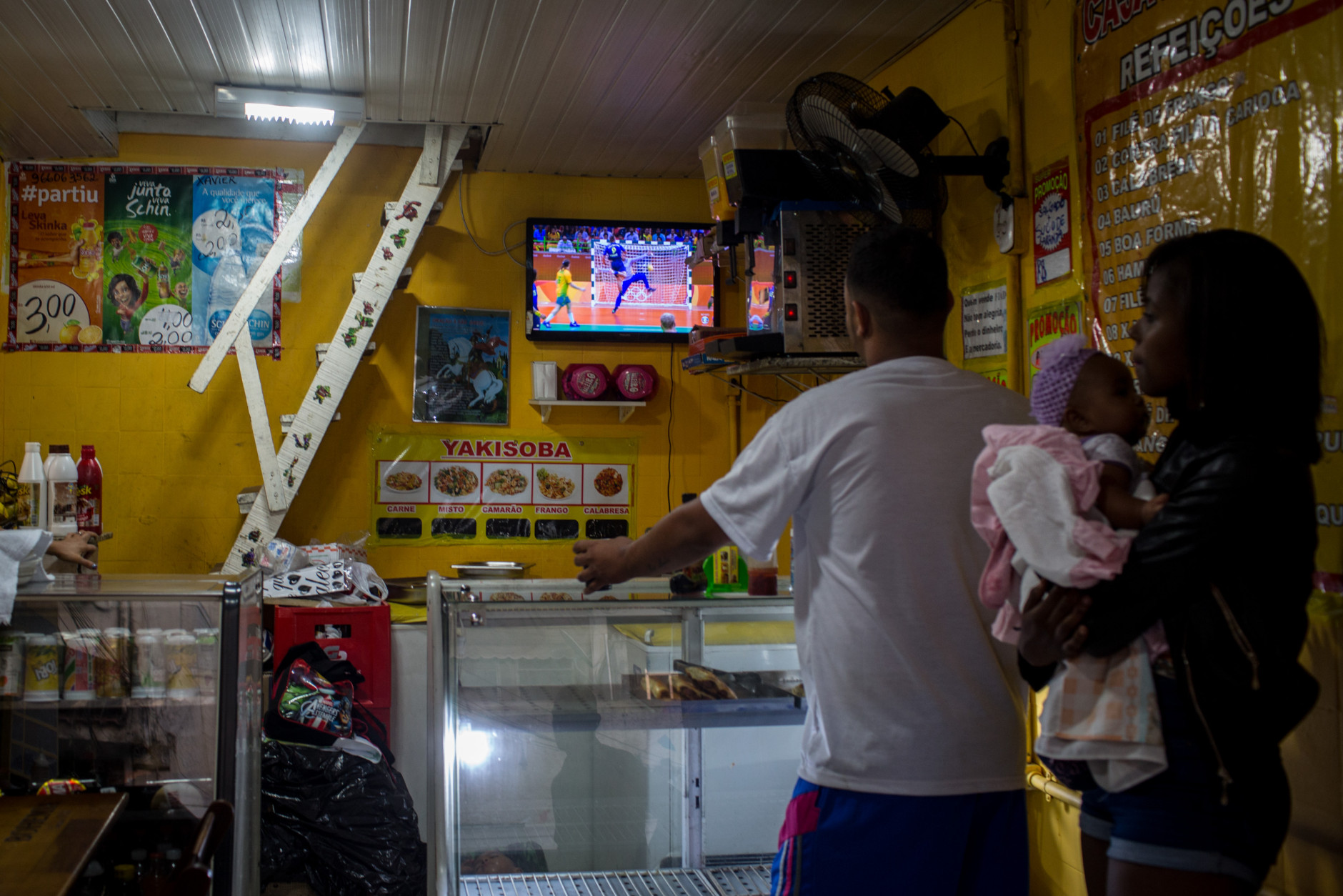 RIO DE JANEIRO, BRAZIL - AUGUST 15:  People watch the Olympic games on a tv screen at a neighbourhood shop on the outskirts of a 'favela' community on August 15, 2016 in Rio de Janeiro, Brazil.  Brazil is currently hosting the 2016 Summer Olympic games despite the dismissal of President Dilma Rousseff, pollution concerns, ongoing crime problems and a failing economy. Around 1.4 million residents, or approximately 22 percent of Rio's population, reside in favelas which often lack proper sanitation, health care, education and security, for many of these residents watching the Olympic games on tv is their only access to the event.  (Photo by Chris McGrath/Getty Images)