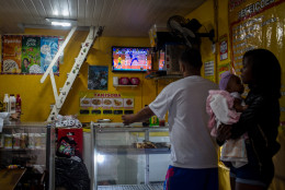 RIO DE JANEIRO, BRAZIL - AUGUST 15:  People watch the Olympic games on a tv screen at a neighbourhood shop on the outskirts of a 'favela' community on August 15, 2016 in Rio de Janeiro, Brazil.  Brazil is currently hosting the 2016 Summer Olympic games despite the dismissal of President Dilma Rousseff, pollution concerns, ongoing crime problems and a failing economy. Around 1.4 million residents, or approximately 22 percent of Rio's population, reside in favelas which often lack proper sanitation, health care, education and security, for many of these residents watching the Olympic games on tv is their only access to the event.  (Photo by Chris McGrath/Getty Images)