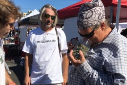 Mark Perry, coordinator of the DC State Fair Best Bud Competition, takes a whiff of the winning bud, “Golden Strawberries.” Sam McBee, (at left) who submitted entry, is pictured here with Samson Paisley. (WTOP/Liz Anderson)