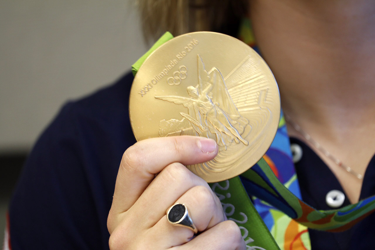 Katie Ledecky holds up one of her gold medals won during the Rio Olympics during a visit to WTOP on Monday, Aug. 29, 2016. (WTOP/Kate Ryan)