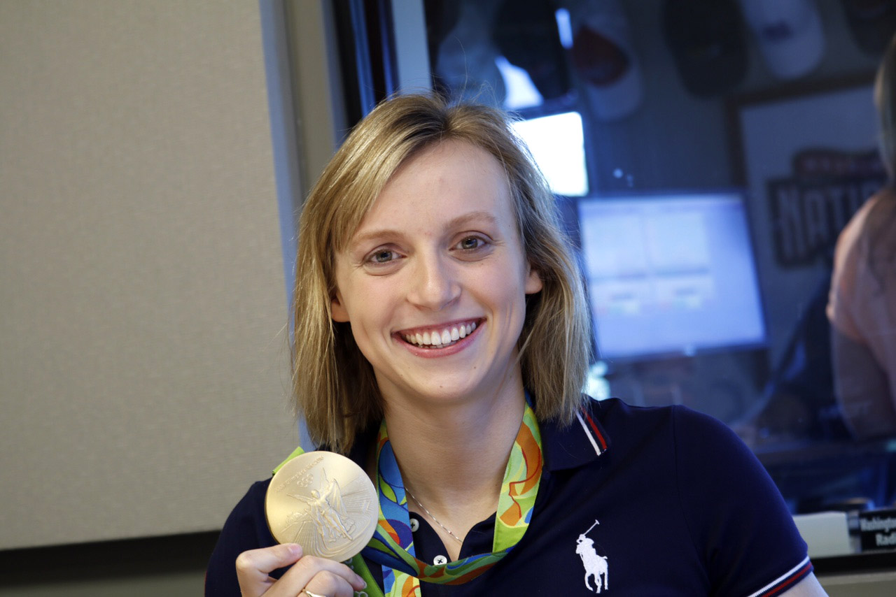 Bethesda swimmer Katie Ledecky holds up one of the four gold medals she won during the 2016 Rio Olympics during a visit to WTOP on Monday, Aug. 29, 2016. (WTOP/Kate Ryan)