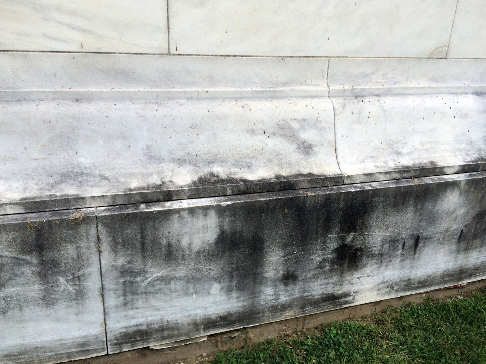 This photo shows the black growth that began coating the sides of the Jefferson Memorial more than a decade ago. The biofilm - a combination of bacteria, fungi and algae, has spread more rapidly in recent years and this week the National Park Service applied various chemical agents to a section of the marble to see if any would remove the film. (WTOP/Nick Iannelli)