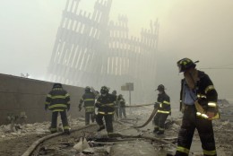 THEN-- With the skeleton of the World Trade Center twin towers in the background, New York City firefighters work amid debris on Cortlandt St. after the terrorist attacks of Tuesday, Sept. 11, 2001.  (AP Photo/Mark Lennihan)