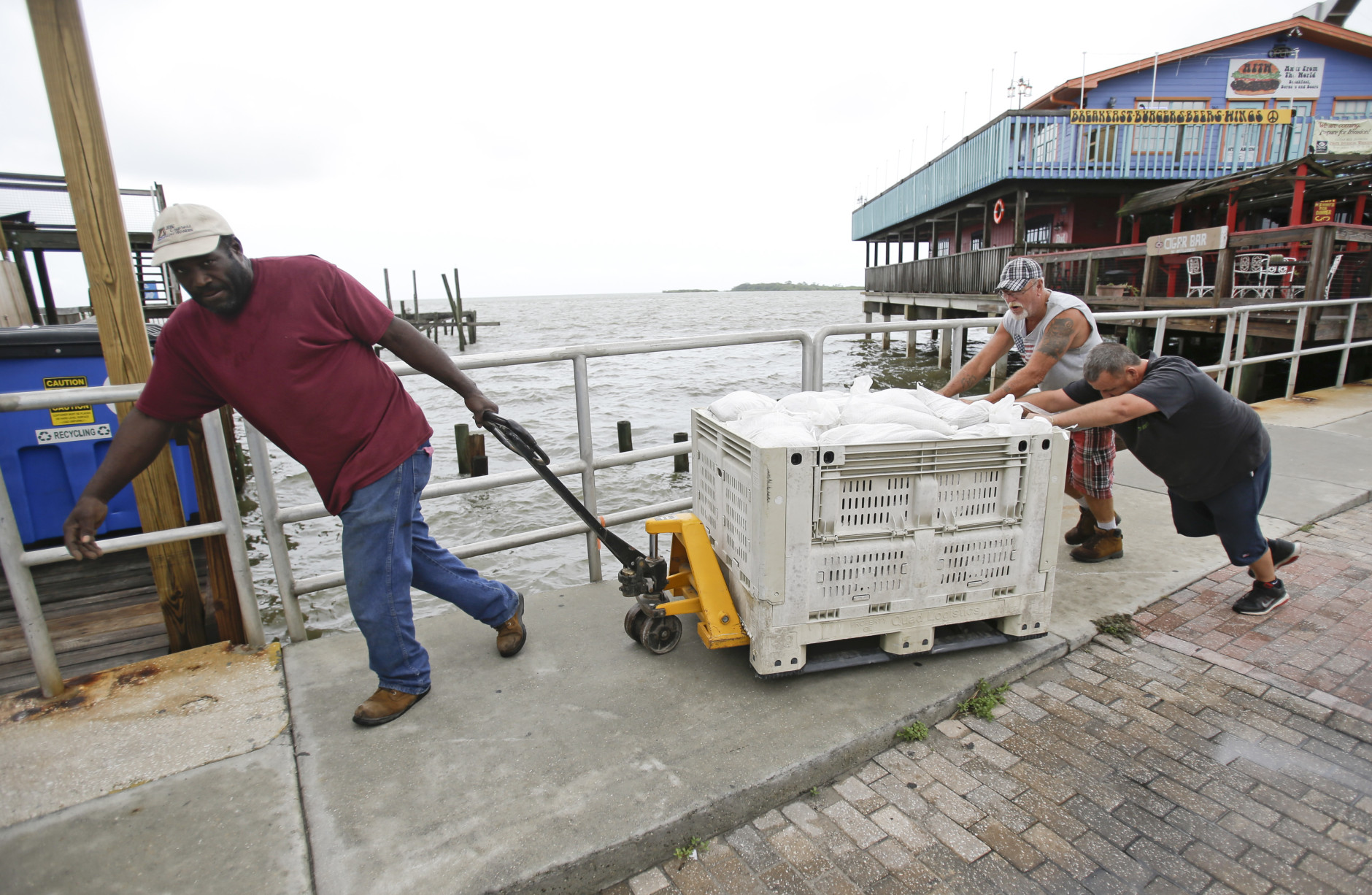 Workers move sandbags to protect a restaurant in preperation for Tropical Storm Hermine Wednesday, Aug. 31, 2016, in Cedar Key, Fla. Forecasters say Hermine could be near hurricane strength by Thursday night as it approaches the Gulf Coast. (AP Photo/John Raoux)