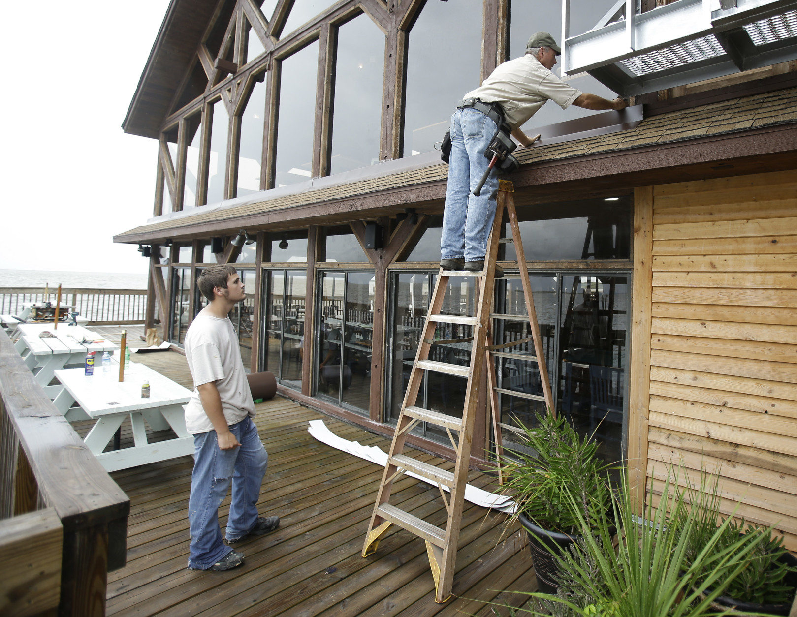 Workers install flashing around the roof and windows of restaurant in preparation of Tropical Storm Hermine Wednesday, Aug. 31, 2016, in Cedar Key, Fla. Forecasters say Hermine could be near hurricane strength by Thursday night as it approaches the Gulf Coast. (AP Photo/John Raoux)