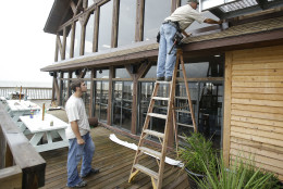 Workers install flashing around the roof and windows of restaurant in preparation of Tropical Storm Hermine Wednesday, Aug. 31, 2016, in Cedar Key, Fla. Forecasters say Hermine could be near hurricane strength by Thursday night as it approaches the Gulf Coast. (AP Photo/John Raoux)