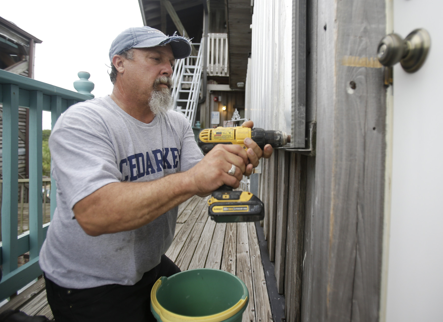 Tony Frazier installs storm shutters on a building in preparation for Tropical Storm Hermine, Thursday, Sept. 1, 2016, in Cedar Key, Fla. (AP Photo/John Raoux)