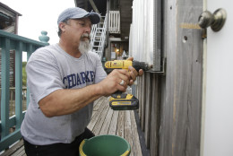 Tony Frazier installs storm shutters on a building in preparation for Tropical Storm Hermine, Thursday, Sept. 1, 2016, in Cedar Key, Fla. (AP Photo/John Raoux)