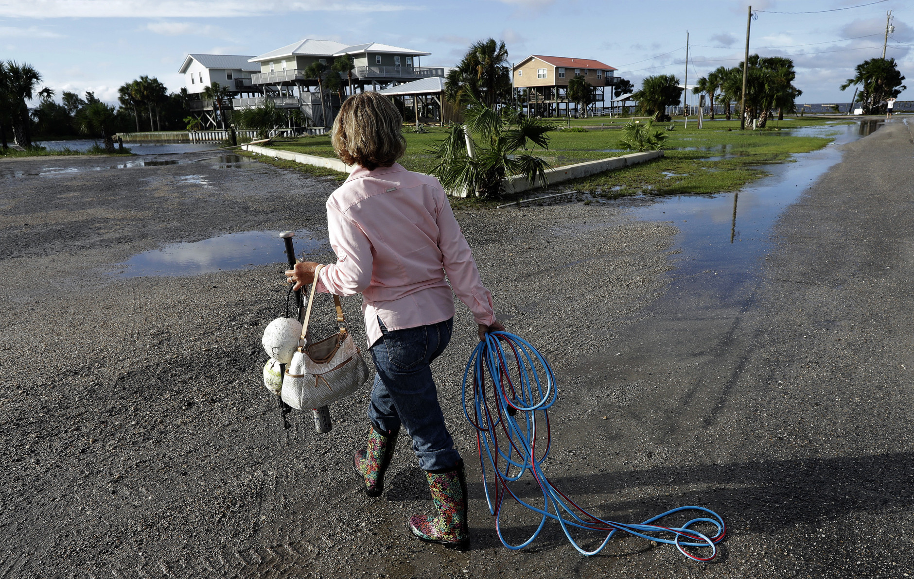Nancy Geohagen picks up some of her belongings after her home was damaged by Hurricane Hermine when it came ashore Friday, Sept. 2, 2016, in , Fla.  Hermine was downgraded to a tropical storm after it made landfall, as it moves over Georgia, but the U.S. National Hurricane Center says winds are increasing along the Southeast coast and flooding rains continue.  (AP Photo/Chris O'Meara)