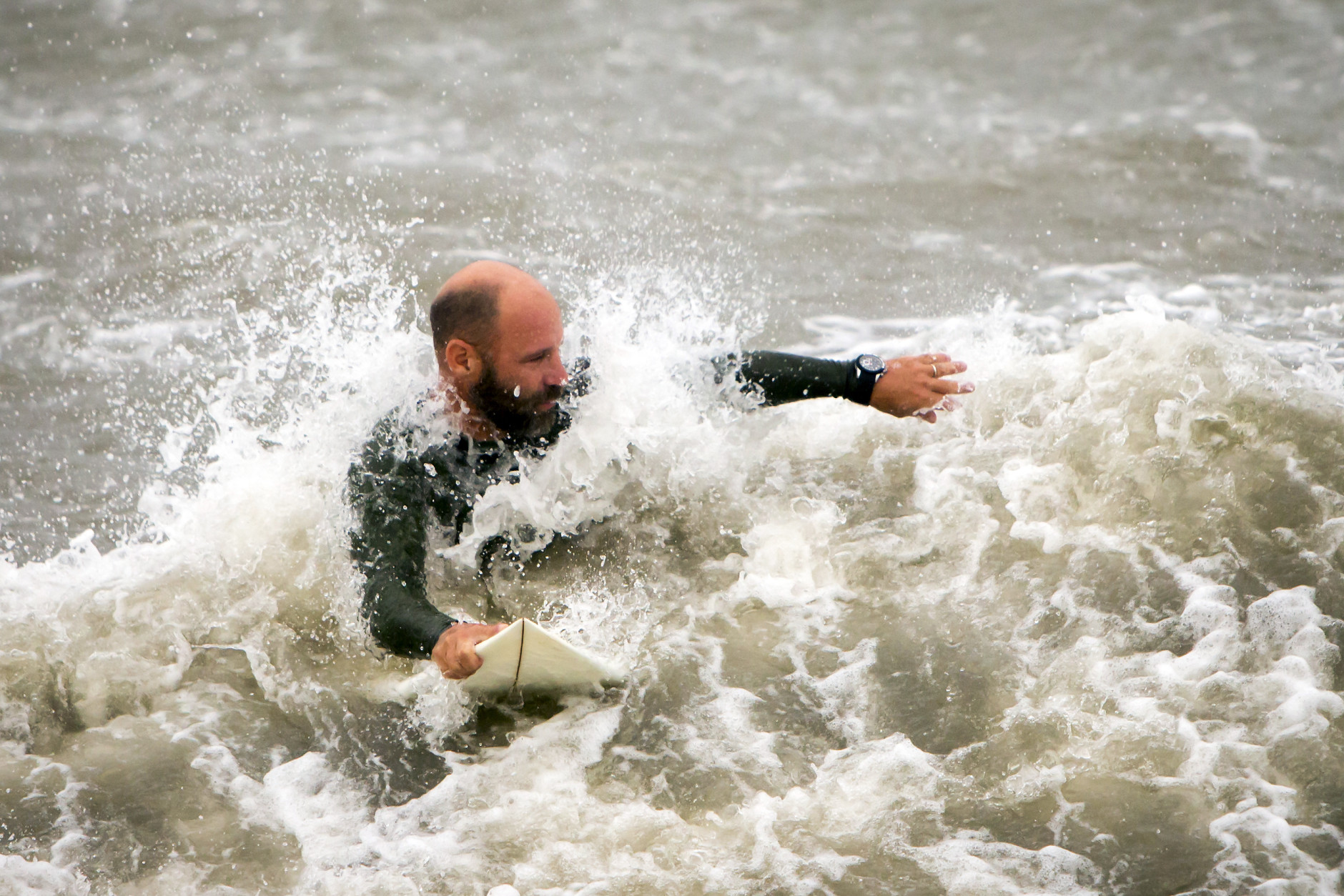 A surfer looks for a wave from the surge of Hurricane Hermine, Friday, Sept. 2, 2016, off the coast of Tybee Island, Ga.  Hermine was downgraded to a tropical storm after it made landfall, as it moves over Georgia, but the U.S. National Hurricane Center says winds are increasing along the Southeast coast and flooding rains continue.  (AP Photo/Stephen B. Morton)