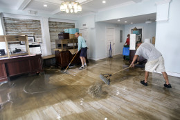Shawn Stephenson, left, and Marshall Dimick clear water from a real estate office that was flooded by Hurricane Hermine Friday, Sept. 2, 2016, in Cedar Key, Fla. Hermine was downgraded to a tropical storm after it made landfall. (AP Photo/John Raoux)