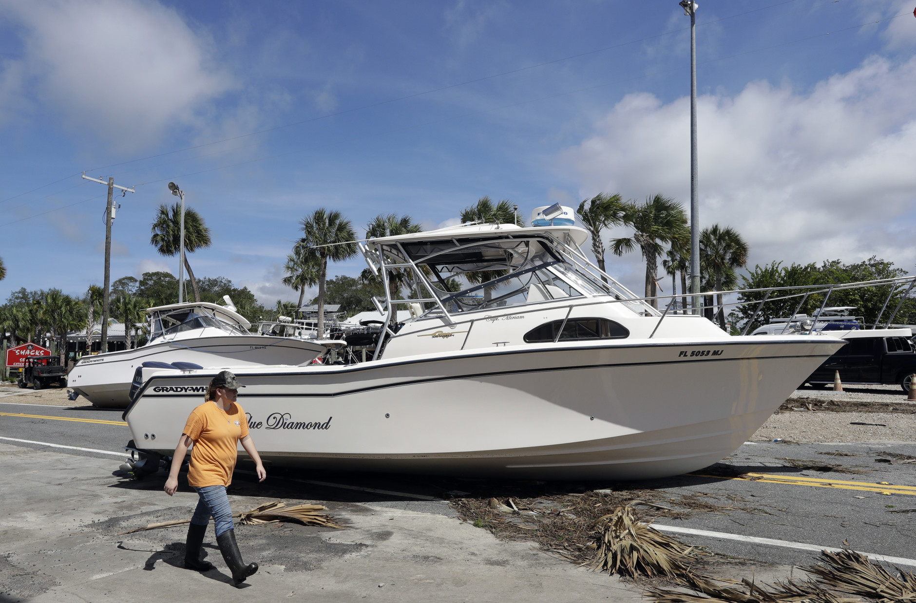 A woman walks past pleasure boats that were washed into Riverside Dr., when Hurricane Hermine came ashore early Friday, Sept. 2, 2016, in Steinhatchee, Fla. Hermine was downgraded to a tropical storm after it made landfall, as it moves over Georgia, but the U.S. National Hurricane Center says winds are increasing along the Southeast coast and flooding rains continue.(AP Photo/Chris O'Meara)