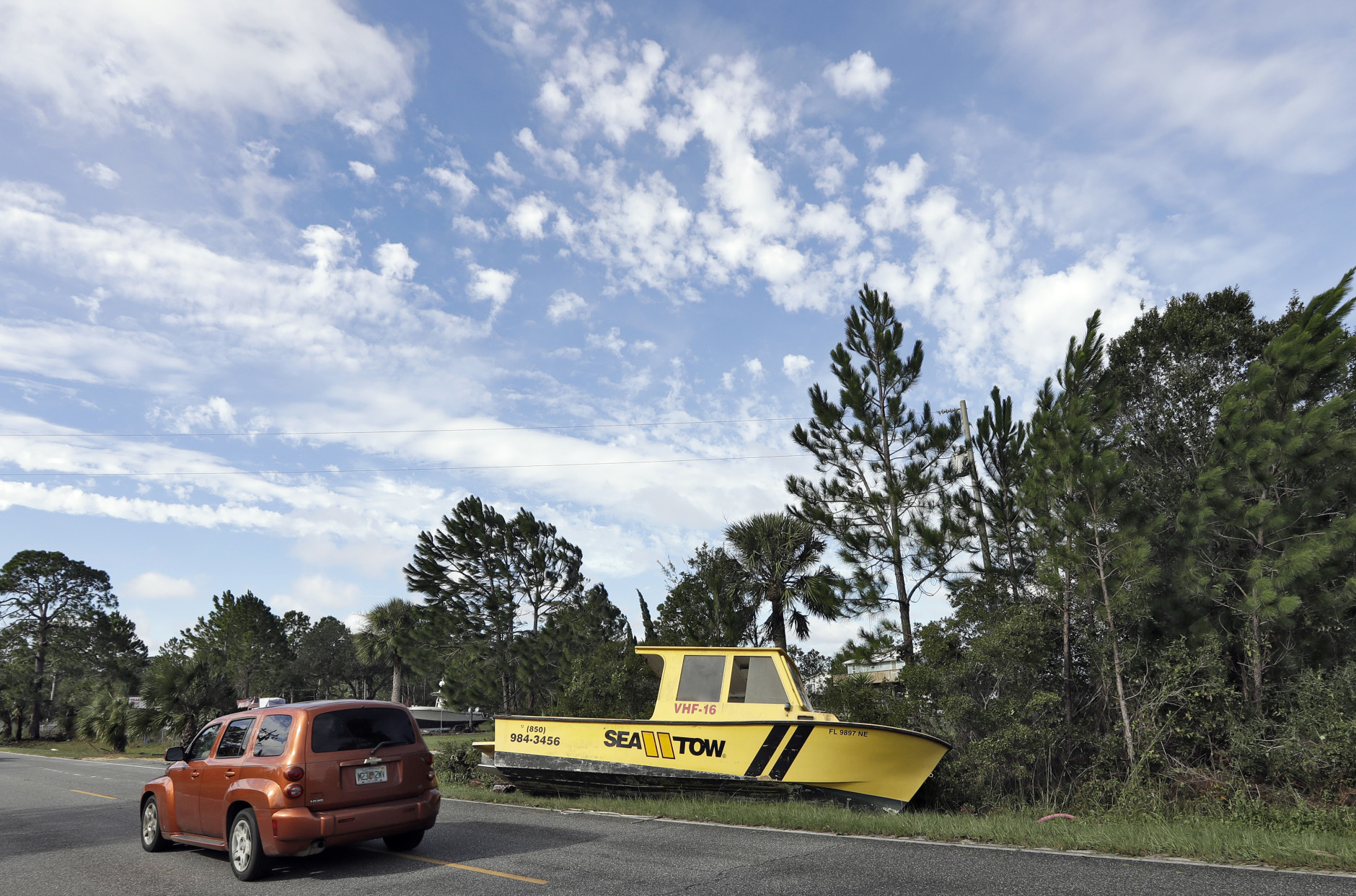 Motorists drive by a boat that was tossed onto the road when winds from Hurricane Hermine came ashore early Friday, Sept. 2, 2016, in Dekle Beach, Fla.  Hermine was downgraded to a tropical storm after it made landfall, as it moves over Georgia, but the U.S. National Hurricane Center says winds are increasing along the Southeast coast and flooding rains continue. (AP Photo/Chris O'Meara)