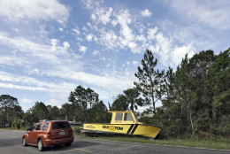Motorists drive by a boat that was tossed onto the road when winds from Hurricane Hermine came ashore early Friday, Sept. 2, 2016, in Dekle Beach, Fla.  Hermine was downgraded to a tropical storm after it made landfall, as it moves over Georgia, but the U.S. National Hurricane Center says winds are increasing along the Southeast coast and flooding rains continue. (AP Photo/Chris O'Meara)