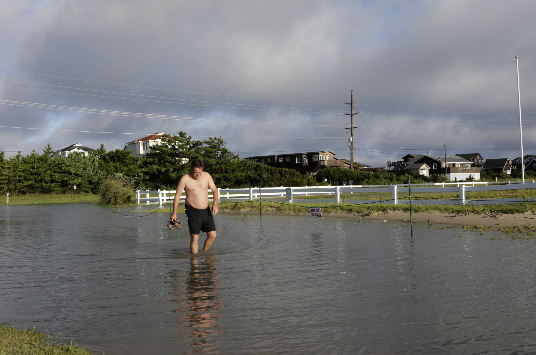 Paul O'Brien of Australia checks the depth of the road near the home he rented for vacation in Rodanthe, N.C., Saturday, Sept. 3, 2016 after Tropical Storm Hermine passed the Outer Banks.  The storm is expected to dump several inches of rain in parts of coastal Virginia, Maryland, Delaware, New Jersey and New York as the Labor Day weekend continues.  (AP Photo/Tom Copeland)