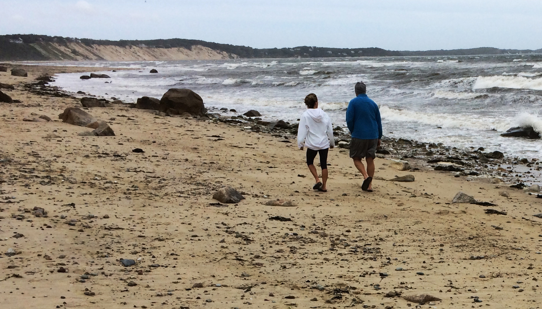 A couple walks along Sagamore Beach as Hermine whips up heavy surf on Cape Cod Bay on Monday, Sept. 5, 2016, in Bourne, Mass. Hermine continued Monday to twist hundreds of miles off shore in the Atlantic Ocean and was expected to keep swimmers and surfers out of beach waters because of its dangerous waves and rip currents on the last day of the long holiday weekend. (AP Photo/William J. Kole)