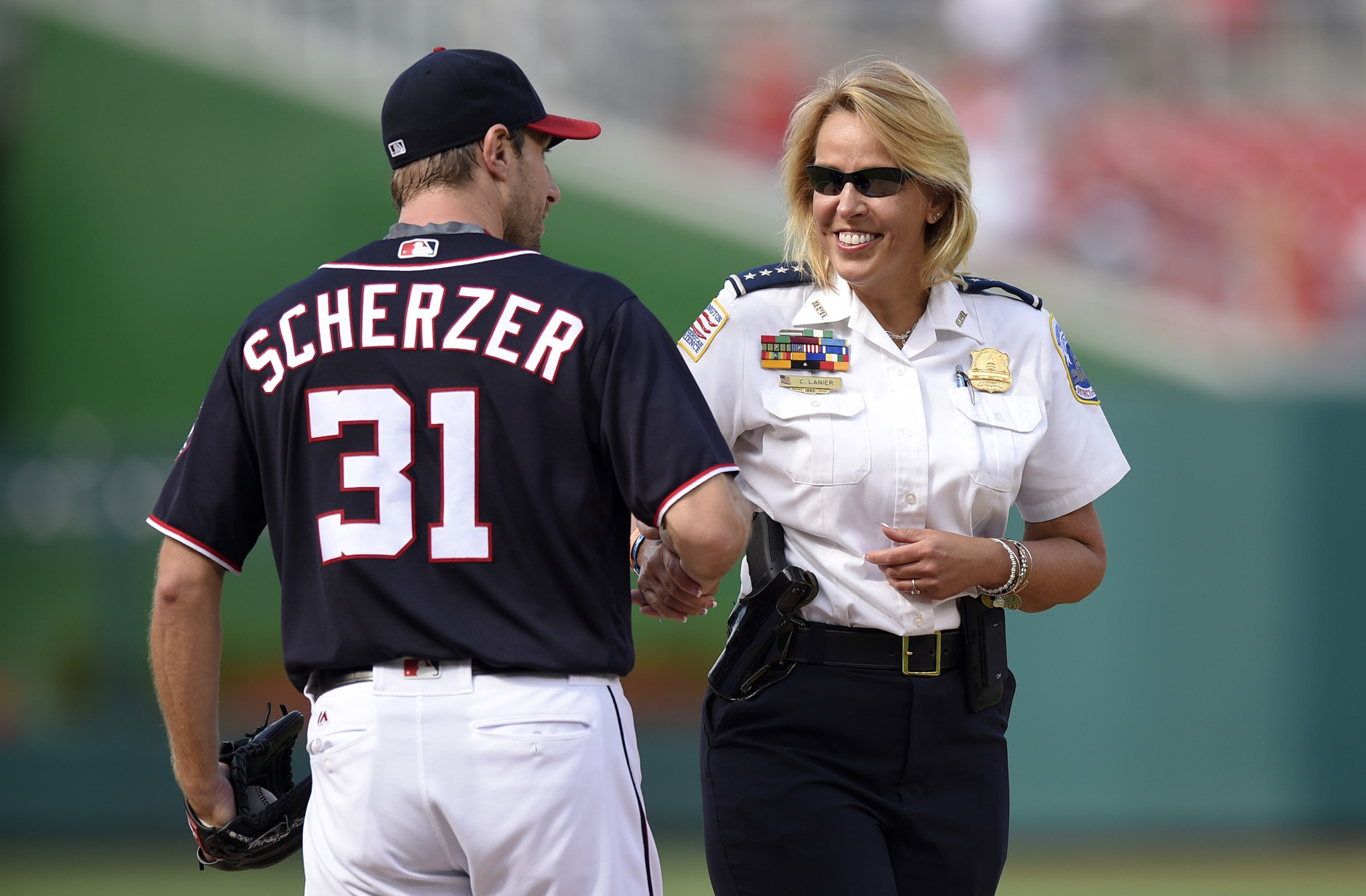 Metropolitan Police Department Chief Cathy Lanier, right, shakes hands with Washington Nationals starting pitcher Max Scherzer (31) after she handed him the game ball before the Nationals' baseball game against the Atlanta Braves, Monday, Sept. 5, 2016, in Washington. (AP Photo/Nick Wass)