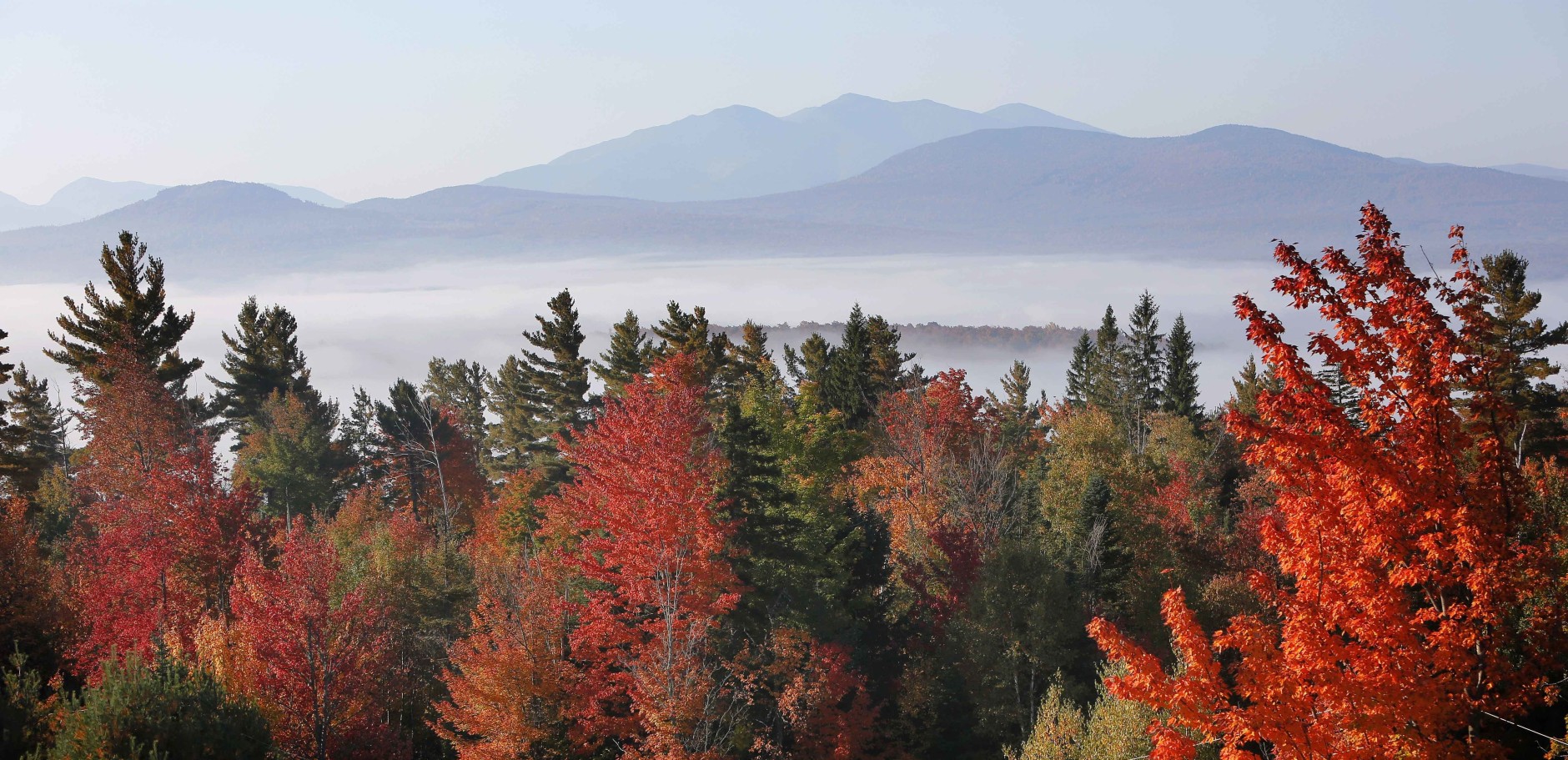 FILE - In this Sept. 28, 2014, file photo, fog sits in the valley of the White Mountains as leaves change colors from Milan Hill in Milan, N.H. (AP Photo/Jim Cole, File)