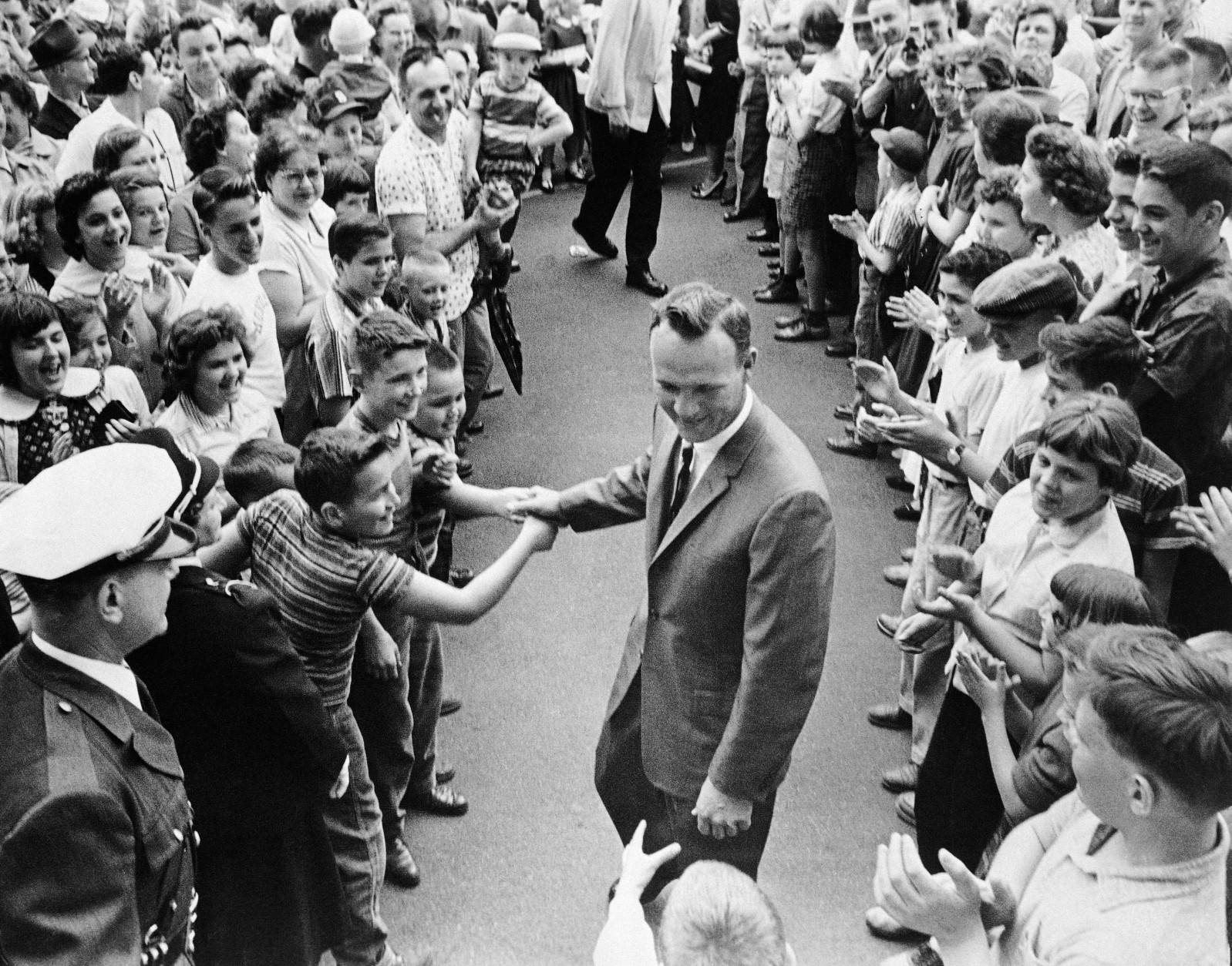 File-This April 16, 1960, file photo shows a grinning Arnold Palmer surrounded by applauding citizens of his native Latrobe,Pa., shaking hands with a couple of enthusiastic boys. Palmer, who made golf popular for the masses with his hard-charging style, incomparable charisma and a personal touch that made him known throughout the golf world as "The King," died Sunday, Sept. 25, 2016, in Pittsburgh. He was 87.  (AP Photo/File)