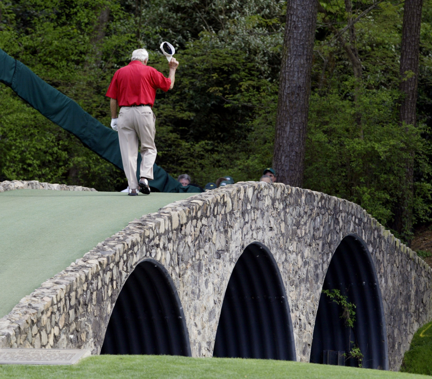 File- This April 9, 2004, file photo shows Arnold Palmer walking across the Hogan Bridge on the 12th fairway for the final time in Masters competition during the second round of the Masters golf tournament at the Augusta National Golf Club in Augusta, Ga.  Palmer, who made golf popular for the masses with his hard-charging style, incomparable charisma and a personal touch that made him known throughout the golf world as "The King," died Sunday, Sept. 25, 2016, in Pittsburgh. He was 87. (AP Photo/Amy Sancetta, File)