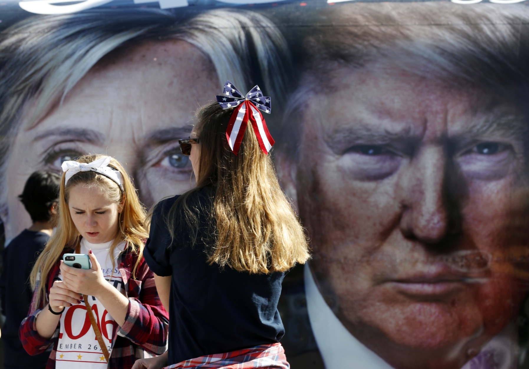 People pause near a bus adorned with large photos of candidates Hillary Clinton and Donald Trump before the presidential debate at Hofstra University in Hempstead, N.Y., Monday, Sept. 26, 2016. (AP Photo/Mary Altaffer)
