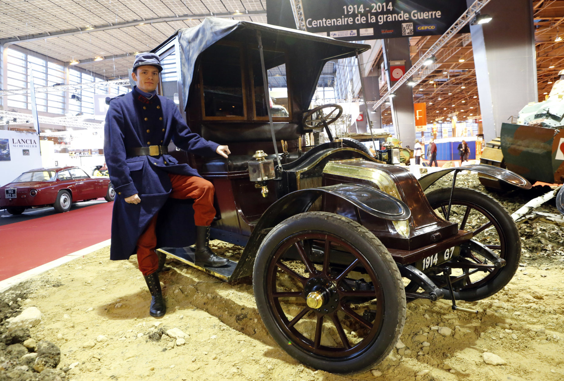 An actor dressed like a WWI soldier poses in front of a 1914 Renault AG1, known as Taxi de la Marne, during the Retromobile vintage cars exhibition, in Paris, Wednesday, Feb. 5, 2014. The exhibition runs until Friday Feb. 7, 2014. The name Taxi de la Marne was not used until the outbreak of World War I, when the fleet of Paris taxis was requisitioned by the French Army to transport troops from Paris to the First Battle of the Marne in early September 1914. (AP Photo/Jacques Brinon)