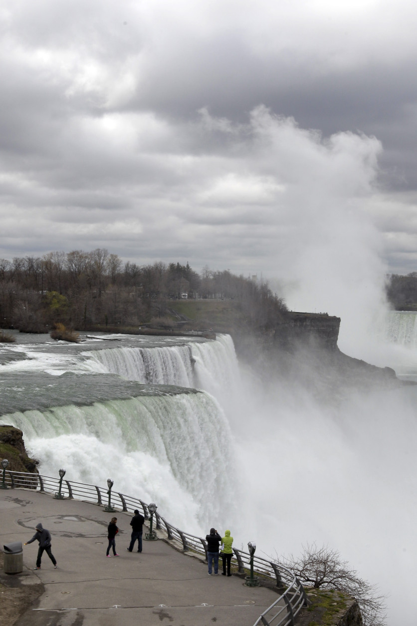 FILE--In this April 11, 2012 file photo, tourists visit the American Falls in Niagara Falls, N.Y. New York officials are considering temporarily turning Niagara Falls into a trickle. State officials are holding a public hearing this week to discuss plans for replacing 115-year-old bridges linking the mainland to islands near the brink of Niagara Falls. To do so, they might reduce the flow on the American side of the falls by building a temporary structure to redirect Niagara River water to the Canadian side. (AP Photo/David Duprey, File)