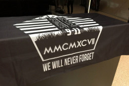 A black shroud with an image depicting the terror attacks at the Pentagon, the World Trade Center and the field in Shanksville, Pennsylvania, includes the Roman numeral 2,997 representing the number of victims killed on Sept. 11. A damaged piece limestone from the attack at the Pentagon was unveiled at Dulles International Airport on Thursday, Sept. 1, 2016. (WTOP/Kristi King)