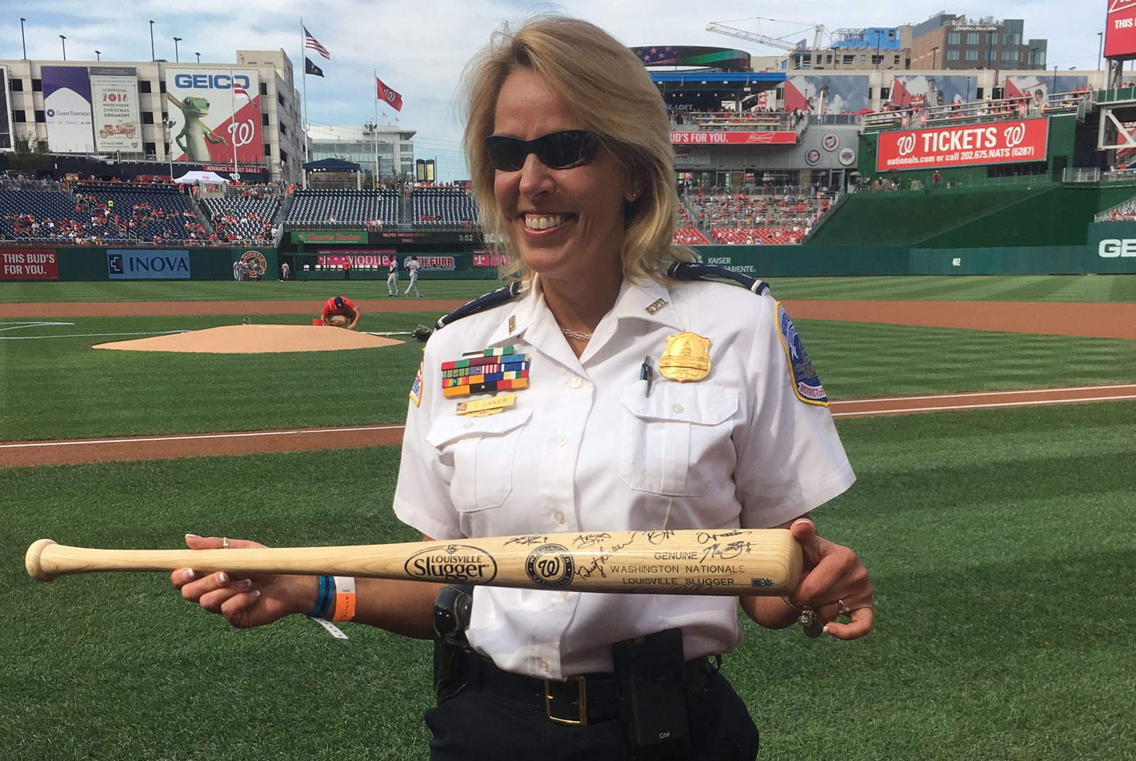 Departing D.C. police Chief Cathy Lanier received a bat signed by all the players of the team before handing off the game ball to Nationals' pitcher Max Scherzer. (WTOP/Mike Murillo)