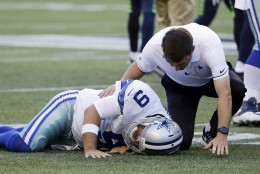 El quarterback de los Cowboys de Dallas Tony Romo es atendido por un entrenador tras una caída durante una jugada contra los Seahawks de Seattle, en la primera mitad de un juego de pretemporada el jueves 25 de agosto de 2016, en Seattle. (AP Foto/Elaine Thompson)