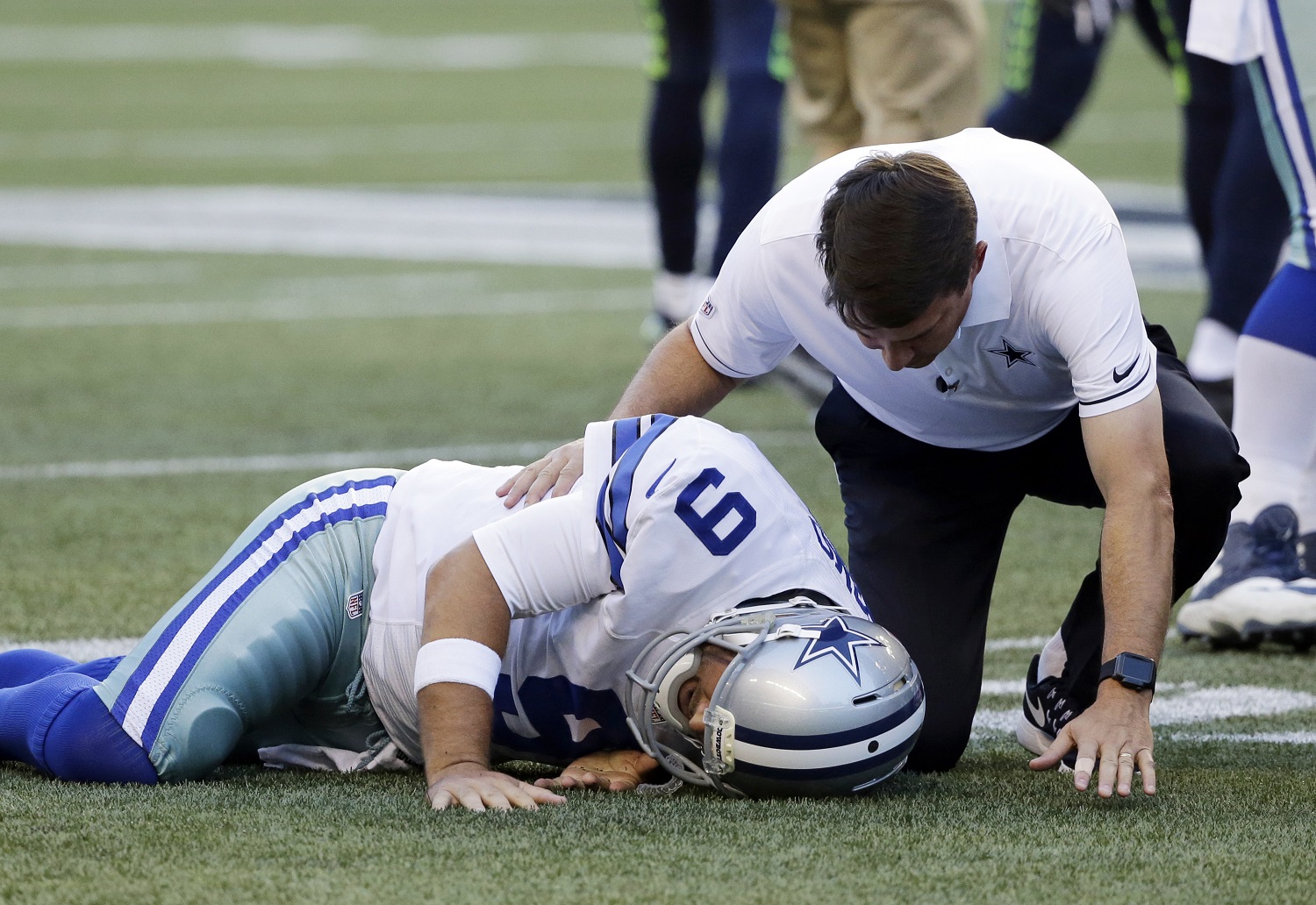 El quarterback de los Cowboys de Dallas Tony Romo es atendido por un entrenador tras una caída durante una jugada contra los Seahawks de Seattle, en la primera mitad de un juego de pretemporada el jueves 25 de agosto de 2016, en Seattle. (AP Foto/Elaine Thompson)