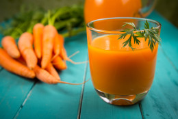 Homemade natural carrot juice in glass on rustic blue wooden table in background