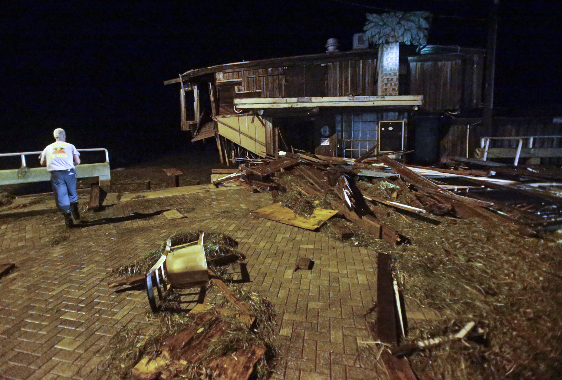 A member of Cedar Key Fire Rescue checks on damage from Hurricane Hermine to a building on the waterfront early Friday, Sept. 2, 2016, in Cedar Key, Fla. Hermine was downgraded to a tropical storm after it made landfall. (AP Photo/John Raoux)