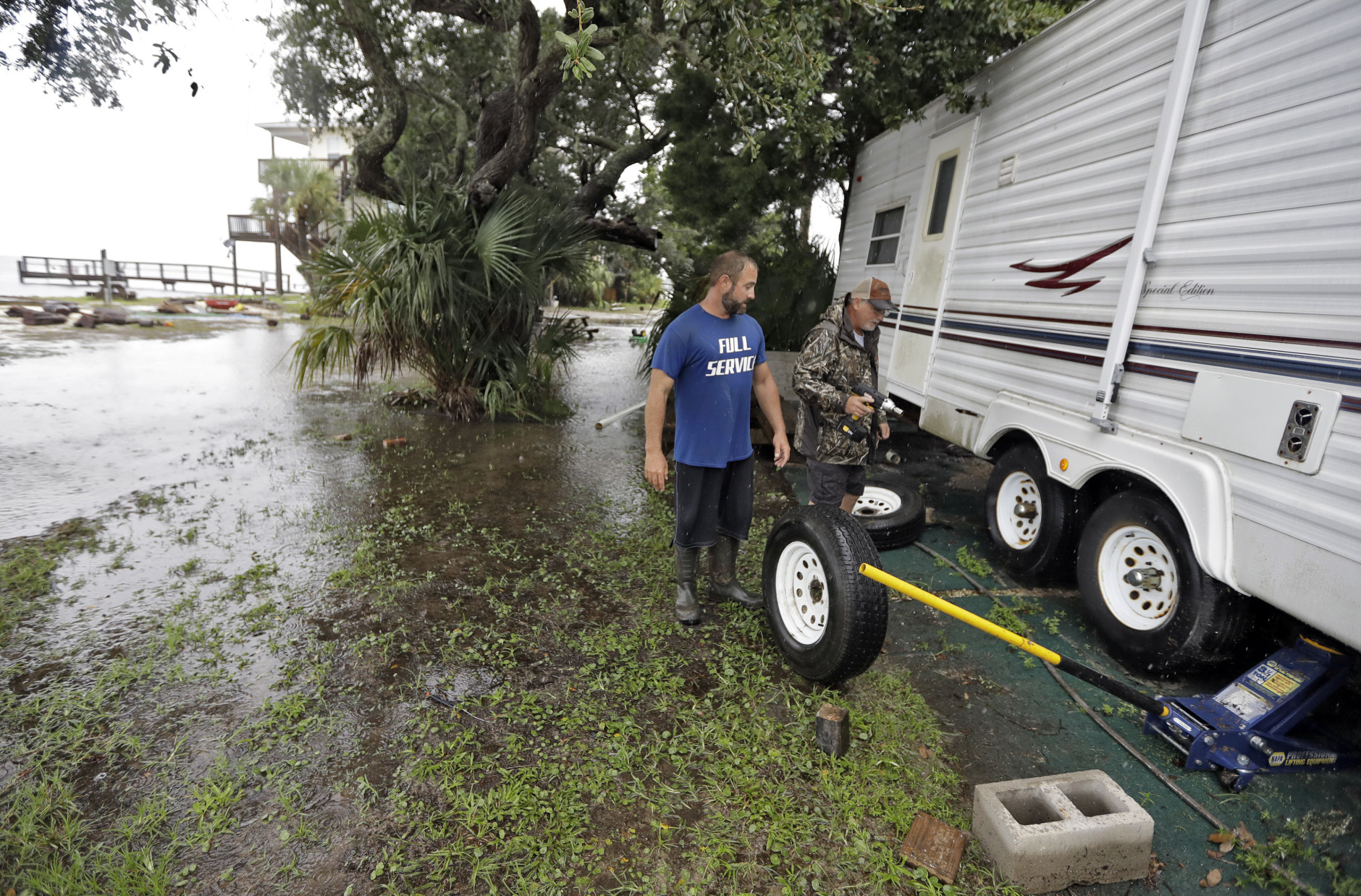 Spyridon Aibejeris, left, helps his neighbors pull out a trailer off their property along the Gulf of Mexico in advance of Tropical Storm Hermine Thursday, Sept. 1, 2016, in Keaton Beach, Fla. Hermine strengthened into a hurricane Thursday and steamed toward Florida's Gulf Coast, where people put up shutters, nailed plywood across store windows and braced for the first hurricane to hit the state in over a decade. (AP Photo/Chris O'Meara)