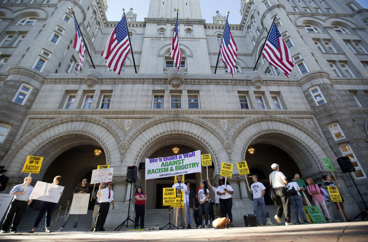 Demonstrators protests in front of the main entrance to the Trump International Hotel in downtown Washington, Monday, Sept. 12, 2016. The luxury hotel Donald Trump has built in an iconic downtown Washington building is set to open. The Trump International Hotel will begin serving guests Monday. There won't be any fanfare around the opening, which is known as a "soft opening." Grand-opening ceremonies are being planned for October. The Trump Organization won a 60-year lease from the federal government to transform the Old Post Office building on Pennsylvania Avenue into a hotel. (AP Photo/Pablo Martinez Monsivais)